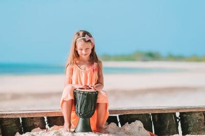 Little happy girl playing on african drums. Little happy girl playing on african drums.
